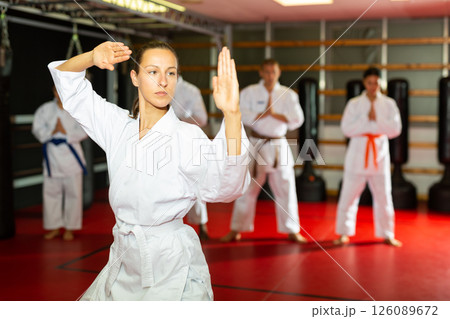 Woman in kimono showing fight stance during karate training Woman in kimono showing fight stance during karate training 126089672