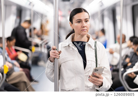Woman using smartphone while traveling in subway car Woman using smartphone while traveling in subway car 126089805