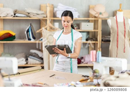 Woman tailor uses tablet when creating drawing of future product Woman tailor uses tablet when creating drawing of future product 126089808