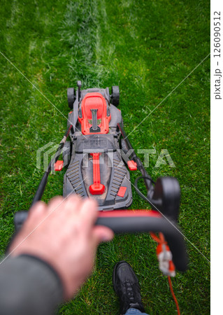 Enjoying a perfect day mowing the lawn on a sunny afternoon in a vibrant green garden Enjoying a perfect day mowing the lawn on a sunny afternoon in a vibrant green garden 126090512