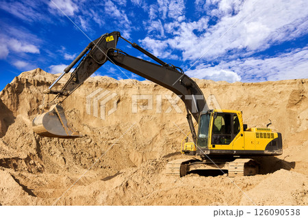 Heavy Excavator Digging Sand at Construction Site Under Blue Sky Heavy Excavator Digging Sand at Construction Site Under Blue Sky 126090538