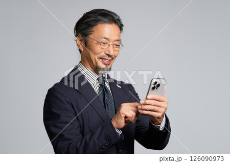 スマホを手にして笑顔を見せるシニアビジネスマン 126090973