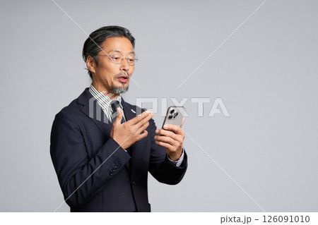 スマホでビデオ通話をするシニアビジネスマン スマホでビデオ通話をするシニアビジネスマン 126091010