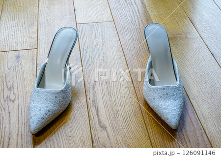 Pair of white sexy high heels mules on a natural wooden floor 126091146