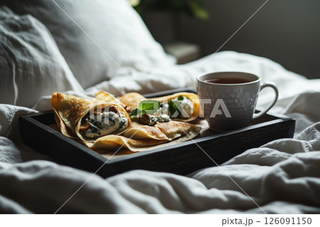 A cozy early morning scene with mini crepes filled with cashew cream, spinach, and fried mushrooms, placed on a rustic wooden tray. Fresh mint tea and soft sunlight complete the serene vibe A cozy early morning scene with mini crepes filled with cashew cream, spinach, and fried mushrooms, placed on a rustic wooden tray. Fresh mint tea and soft sunlight complete the serene vibe 126091150