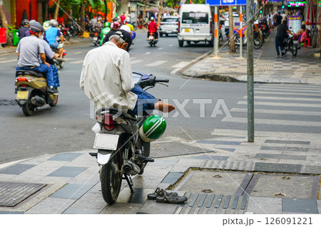 An amazing motorbike taxi driver waits for a customer while relaxing on his motorbike on the street 126091221