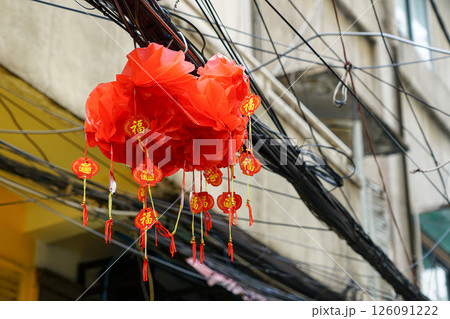 Traditional Chinese red paper lantern with inscriptions blessing hanging in tangle of wires 126091222