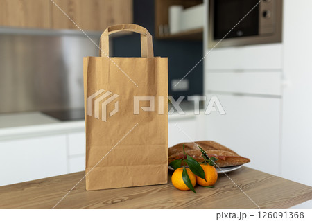 Paper bag on wooden table in kitchen, space for text Paper bag on wooden table in kitchen, space for text 126091368