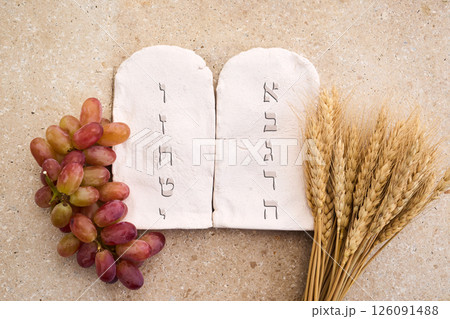 Happy Shavuot concept. Two Stones with Ten Commandments in Ancient Hebrew, Grains, milk and cheese 126091488