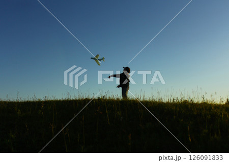 A little boy is playing outside with a toy airplane that he made himself. childhood 126091833