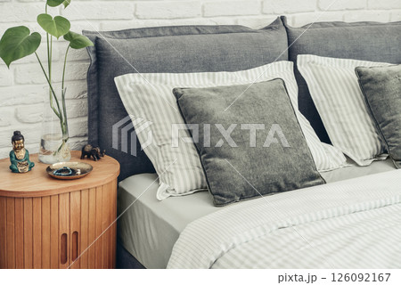 Stylish big comfortable grey bed with striped bed linen Stylish big comfortable grey bed with striped bed linen 126092167