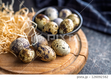 Spotted quail eggs on wooden cutting board on black table. Spotted quail eggs on wooden cutting board on black table. 126092382