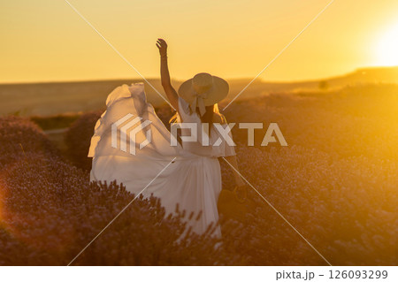 Woman Sunset Lavender Field: Joyful woman in white dress celebrates sunset in a purple lavender field. Woman Sunset Lavender Field: Joyful woman in white dress celebrates sunset in a purple lavender field. 126093299