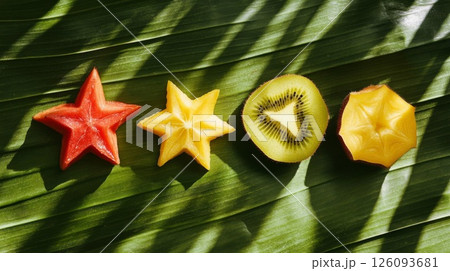 Sliced Tropical Fruits on Green Leaf Background 126093681