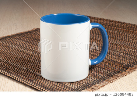 Two-tone 11oz mug on the straw mat on the table. Mug with bluehandle and inner part. Two-tone 11oz mug on the straw mat on the table. Mug with bluehandle and inner part. 126094495