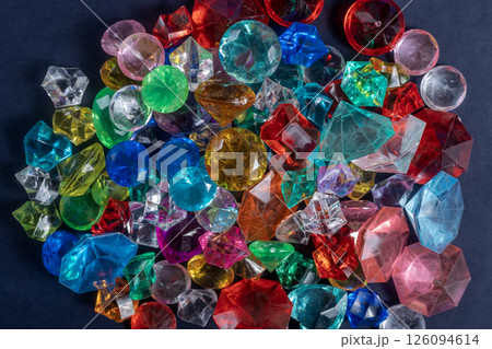 Pile of colorful assorted gemstones shimmering against a dark background. 126094614