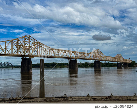 Yellow Truss Bridge Spanning a River Under a Cloudy Blue Sky 126094824