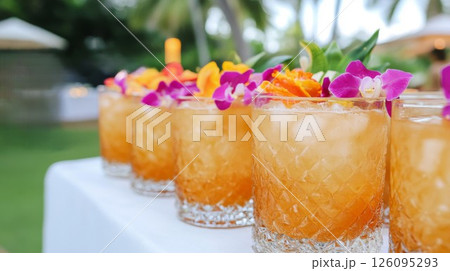 Row of Refreshing Amber Cocktails Garnished with Orchids and Citrus 126095293