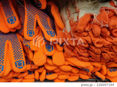 bright orange work gloves stacked in retail store showcasing durable options various tasks. 126097194