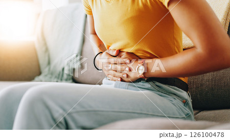 Home, woman and hands with pain for stomach, menstrual cramps and discomfort on sofa in living room. Closeup, female person and ache on couch for colon inflammation, abdomen health and constipation Home, woman and hands with pain for stomach, menstrual cramps and discomfort on sofa in living room. Closeup, female person and ache on couch for colon inflammation, abdomen health and constipation 126100478