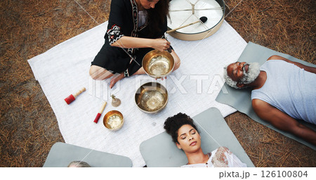Above, sound therapy and woman with bowls in park for mindfulness, spiritual cleanse and energy. Nature, meditation ritual and men and women with vibration for healing, balance and wellness by ocean 126100804