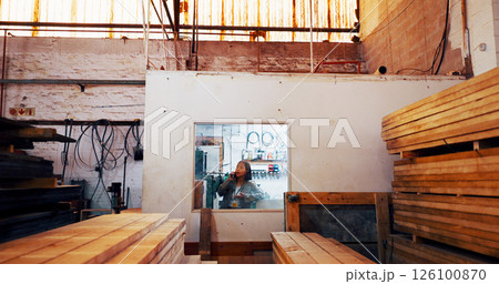 Woman, phone call and talk at warehouse for wood, order or stock for construction material at plant. Person, smartphone and inventory with timber for manufacturing, storage or production at factory Woman, phone call and talk at warehouse for wood, order or stock for construction material at plant. Person, smartphone and inventory with timber for manufacturing, storage or production at factory 126100870