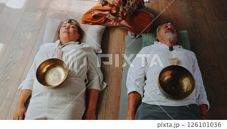 Tibetan bowl, meditation and energy with couple in studio for spiritual healing, aura cleanse and sound therapy. Holistic vibration, crystal and zen with people for mindfulness and wellness ritual 126101036