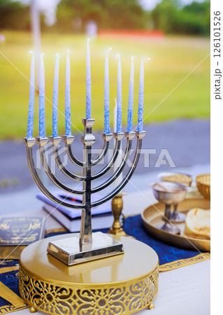 Menorah silver candelabrum holding blue candles is place table at gathering, during Jewish holy festivities Menorah silver candelabrum holding blue candles is place table at gathering, during Jewish holy festivities 126101526