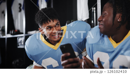 Football, phone and friends or men in locker room for rookie drafting, pro league research and contact. Game score update, team roster with people for connection, training schedule and player stats 126102410