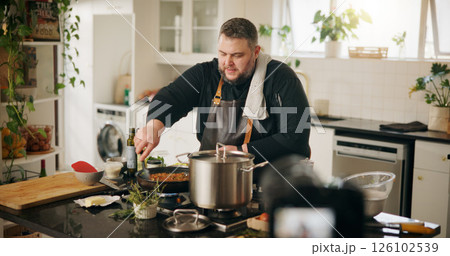 Food, cooking and man with live streaming in home for gourmet recipe tutorial, meal prep and recording. Content creator, chef and filming video with dinner instructions and nutrition tips in kitchen Food, cooking and man with live streaming in home for gourmet recipe tutorial, meal prep and recording. Content creator, chef and filming video with dinner instructions and nutrition tips in kitchen 126102539