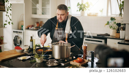 Class, cooking and man with live streaming in kitchen for online tutorial, dinner meal and recipe recording. Culinary influencer, content creation and person with cuisine preparation and vlog in home 126102683