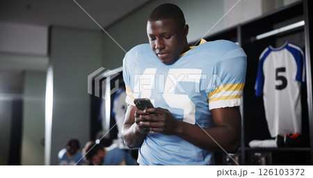 Football, phone and reading with man in locker room for rookie drafting, pro league research and contact. Game score update, team roster with person for connection, training schedule and player stats 126103372