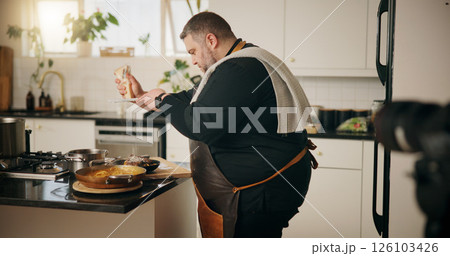 Man, chef and recording in kitchen with food, dinner or recipe online for content creation. Camera, cooking and influencer person with equipment for live streaming, diet advice and meal in home 126103426