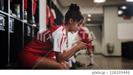 Locker room, online and woman with smartphone, smile and browsing of video on social media and watching. Happy, football player and person with mobile for streaming, healthy and girl with sportswear 126103448
