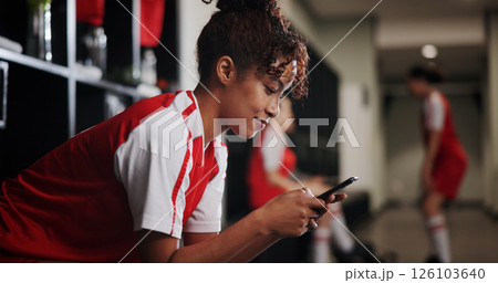 Fitness, watching and woman with smartphone, locker room and browsing of video on social media and online. Happy, football player and person with mobile for streaming, healthy or girl with sportswear 126103640