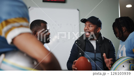 Mentor, man and football with coach and team in locker room for game plan, sports strategy or defense formation. Touchdown tactics, half time feedback and discussion with people and match advice Mentor, man and football with coach and team in locker room for game plan, sports strategy or defense formation. Touchdown tactics, half time feedback and discussion with people and match advice 126103939