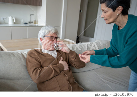 Caregiving wife offer pills and water for heart and blood pressure to weak husband, help ailing man 126103970
