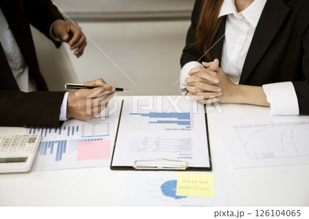 Businessman holding a pen and talking to businesswoman 126104065
