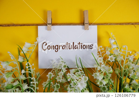 Congratulations text on paper card with flower blooming decoration on yellow background 126106779