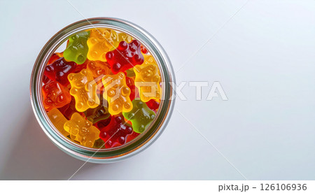 Colorful gummy bears in round glass jar viewed from above on minimal background 126106936