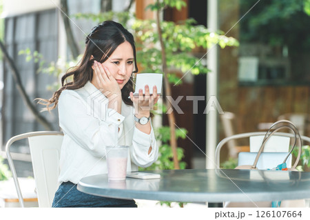 カフェでメイク直し・化粧・メイク・鏡を見る若い女性（保湿・UVカット・紫外線対策） 126107664