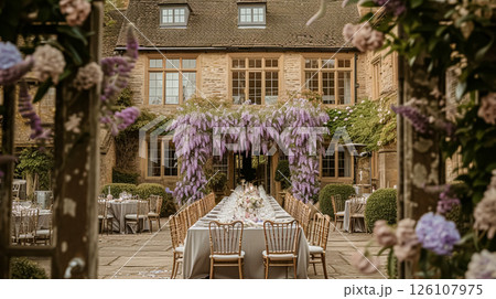 Elegant outdoor dining table set for a celebration in a beautiful garden with a historic building backdrop and purple lavender bushes. 126107975