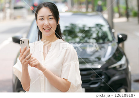 車の前でスマホを操作する若い女性 車の前でスマホを操作する若い女性 126109187