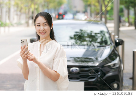 車の前でスマホを操作する若い女性 車の前でスマホを操作する若い女性 126109188