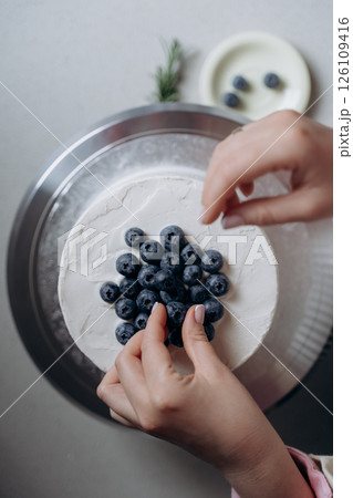 Decorating a Cake with Fresh Blueberries and Cream 126109416