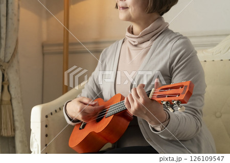 ソファーに座ってウクレレを弾くシニア女性 126109547