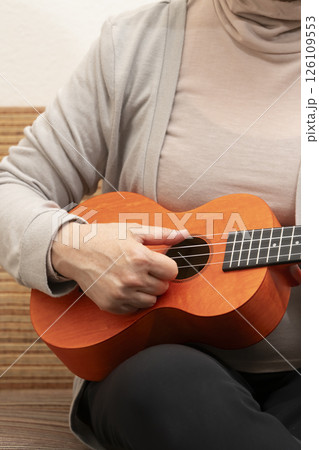 ソファーに座ってウクレレを弾くシニア女性 126109553