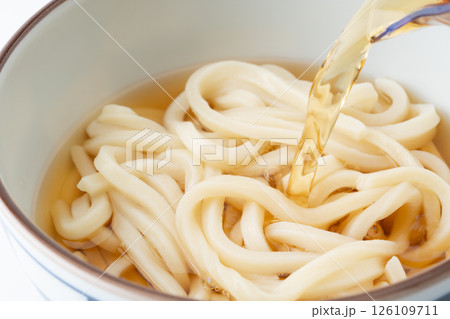 美味しそうなうどんに注ぐ汁のクローズアップ 126109711