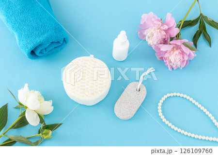 Towel with body care products and peony flowers on the blue background. Towel with body care products and peony flowers on the blue background. 126109760
