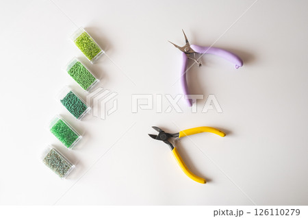 Craft tools and green beads on white surface for jewelry making and design Craft tools and green beads on white surface for jewelry making and design 126110279